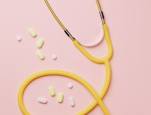 yellow stethoscope and medicines on pink background